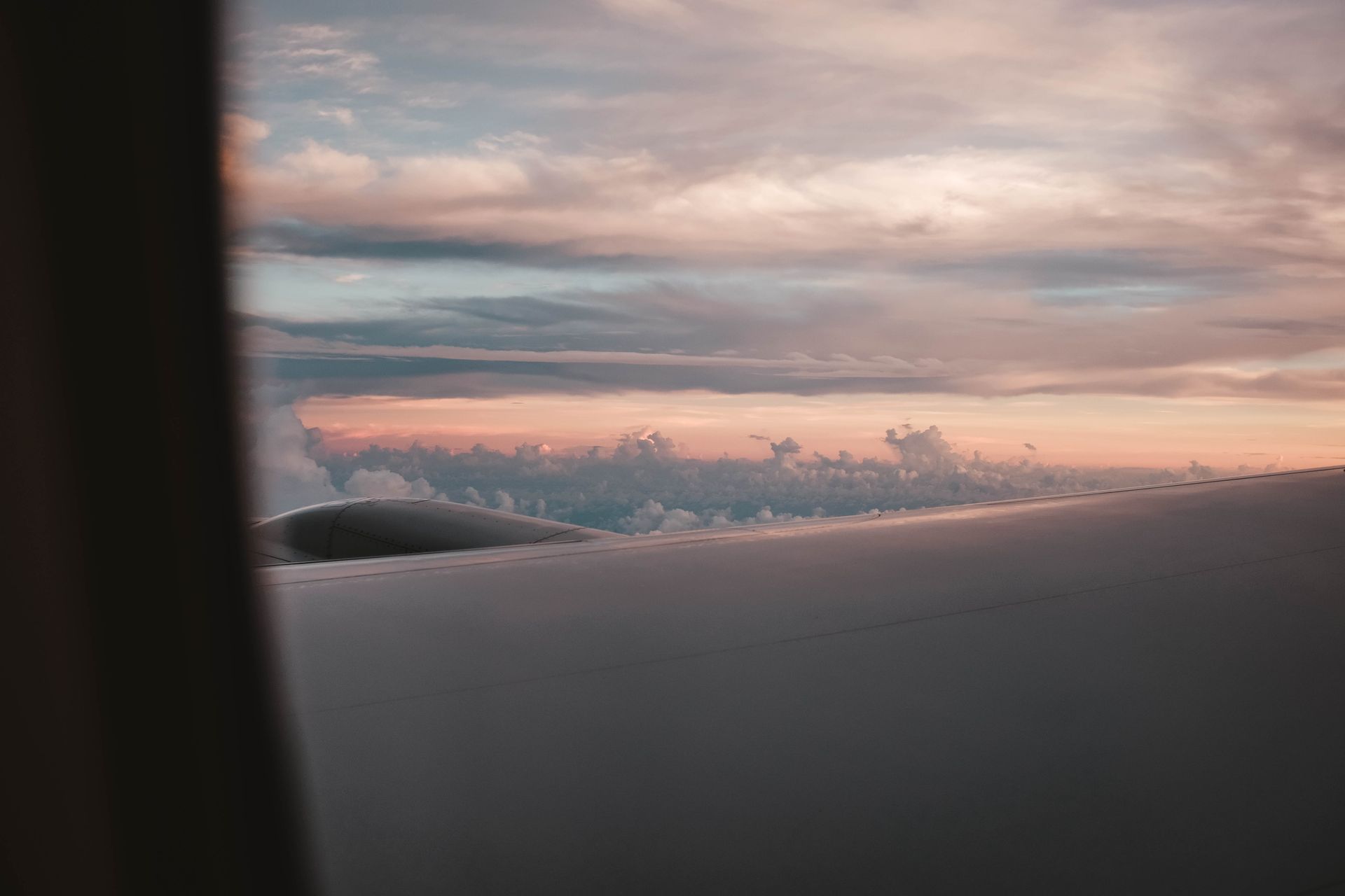 View from an airplane window over clouds at sunset