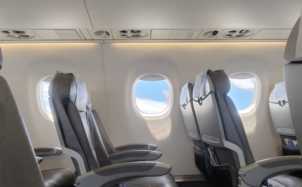 Rows of leather seats in a bright airplane cabin